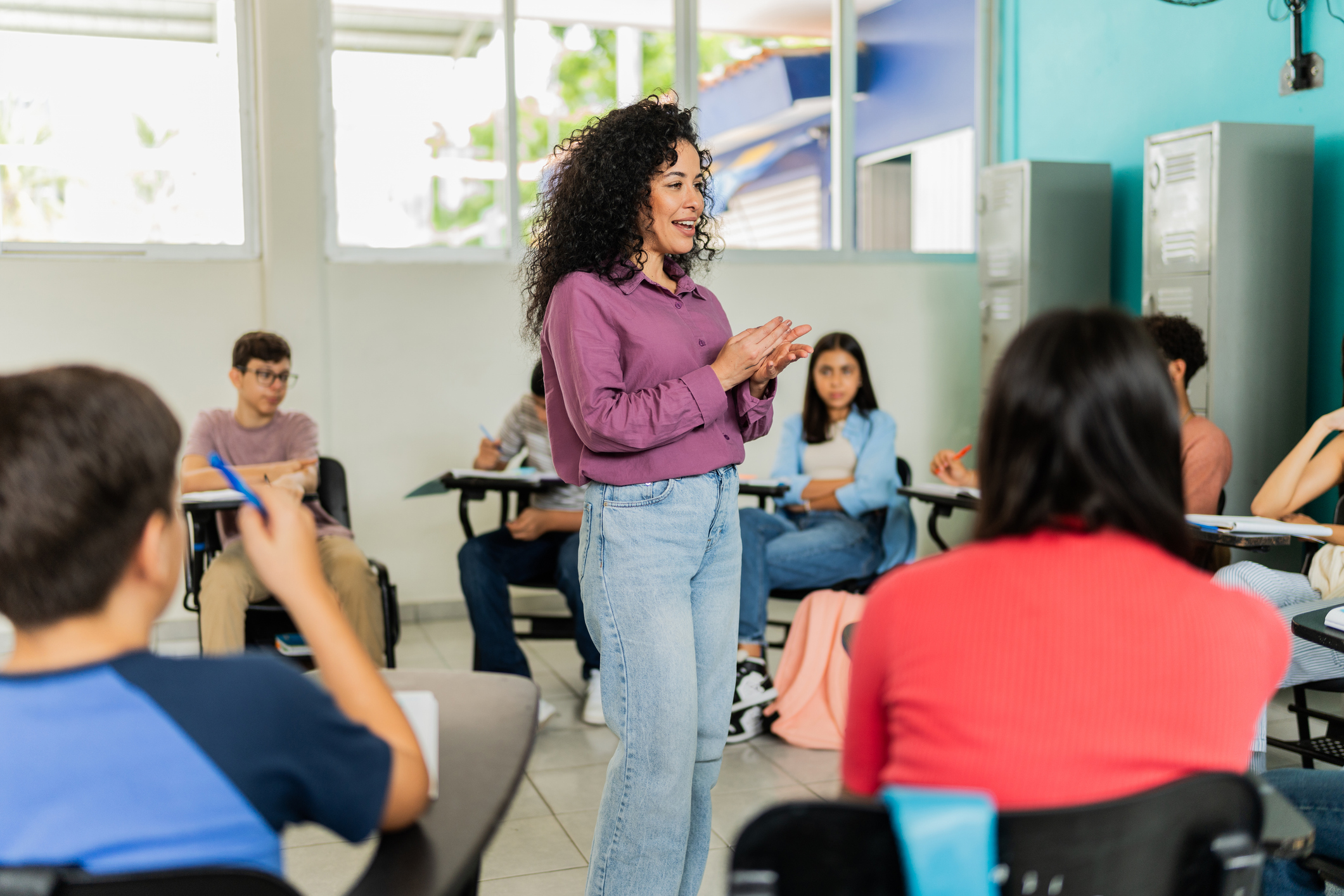 Mid adult teacher teaching students during class at classroom stock photo